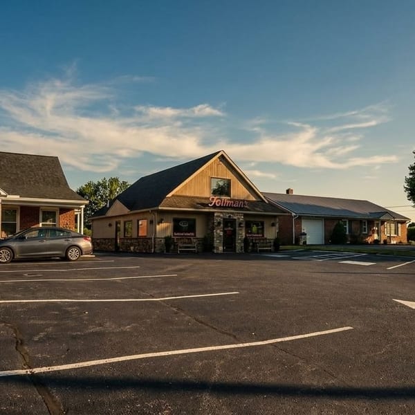 Exterior view of Tillman's restaurant with a large parking lot and surrounding buildings under a blue sky.