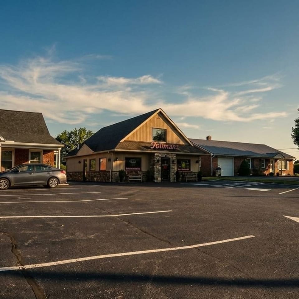 Exterior view of Tillman's restaurant with a large parking lot and surrounding buildings under a blue sky.