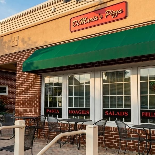DiMaria's Pizza restaurant exterior with green awnings, brick facade, and outdoor patio seating.